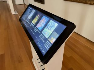 A long touch display mounted on a stand is shown from the side
