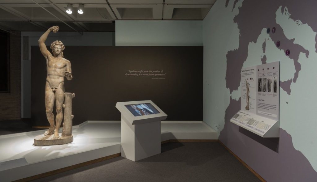 A large interactive kiosk furniture placed in front of a marble sculpture of the greek god Bacchus